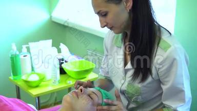 一个年轻的女孩在一个接待与美容师。 美容师正在准备洗脸.. 脸部按摩。